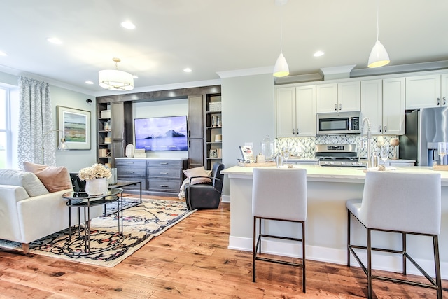 kitchen featuring pendant lighting, light countertops, appliances with stainless steel finishes, open floor plan, and white cabinetry