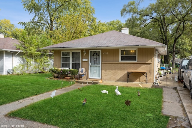 ranch-style home featuring roof with shingles, a chimney, a front lawn, and brick siding