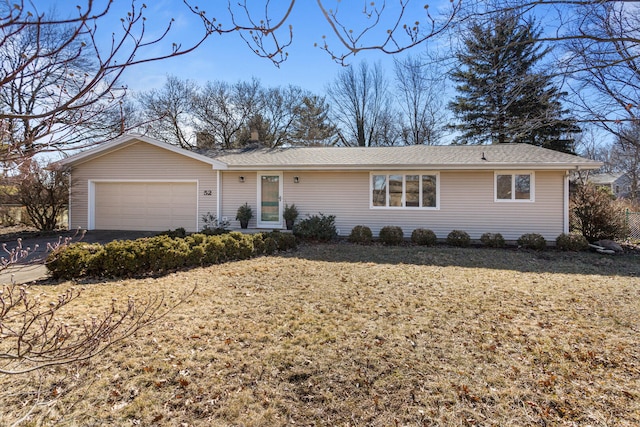 ranch-style home with driveway, an attached garage, and a front yard