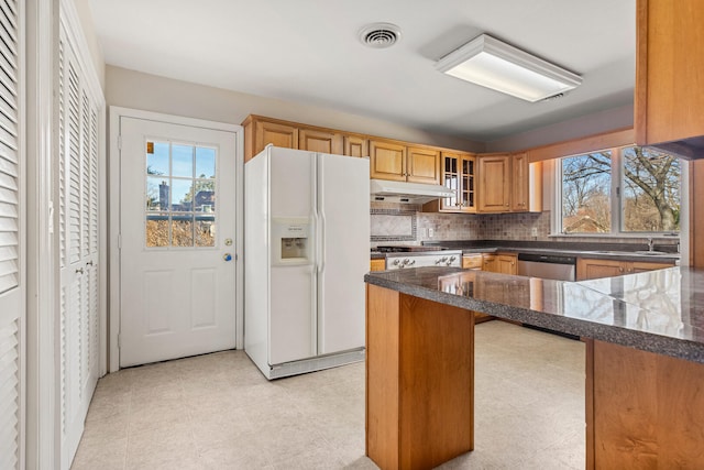 kitchen with under cabinet range hood, white refrigerator with ice dispenser, visible vents, dishwasher, and light floors