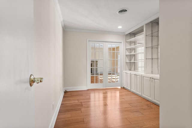 empty room featuring french doors, light wood finished floors, visible vents, ornamental molding, and baseboards