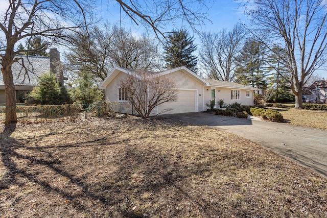 view of side of home featuring an attached garage, driveway, a chimney, and fence