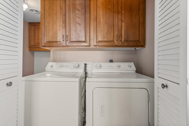 clothes washing area with separate washer and dryer, cabinet space, and visible vents