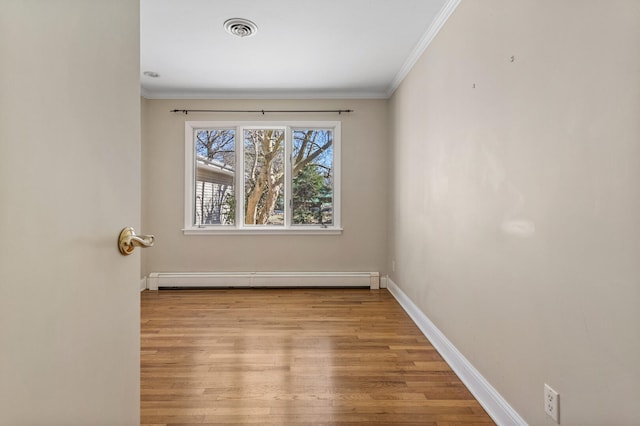 unfurnished room with baseboard heating, wood finished floors, visible vents, and crown molding