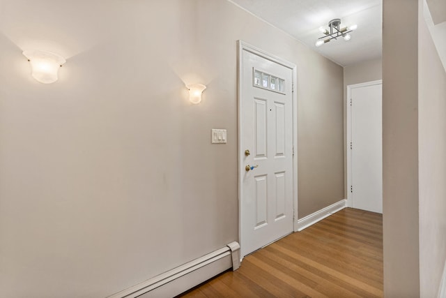 foyer entrance with a baseboard heating unit and wood finished floors