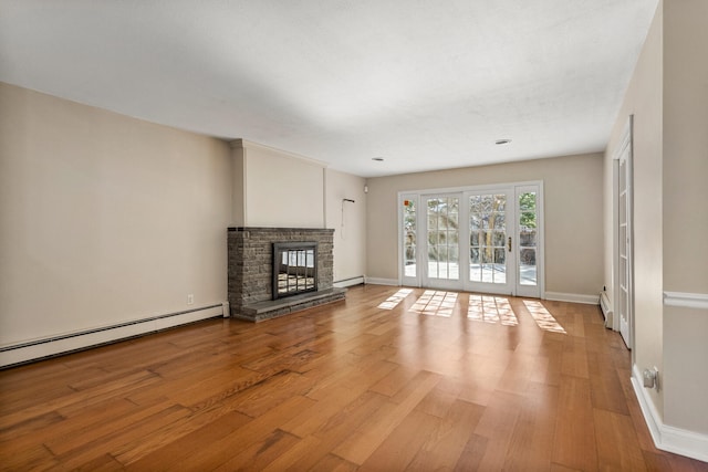 unfurnished living room featuring light wood-type flooring, a stone fireplace, baseboards, and a baseboard radiator