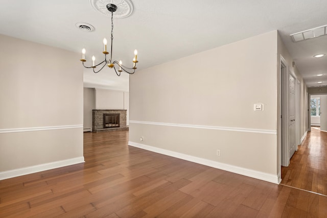 unfurnished dining area featuring visible vents, a fireplace, baseboards, and wood finished floors