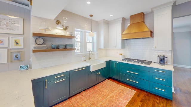 kitchen with white cabinetry, premium range hood, stainless steel gas cooktop, and a sink