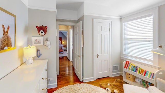 bedroom featuring dark wood-style floors, a closet, visible vents, ornamental molding, and baseboards