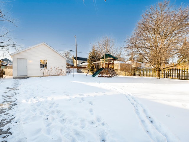 snowy yard featuring a playground and fence