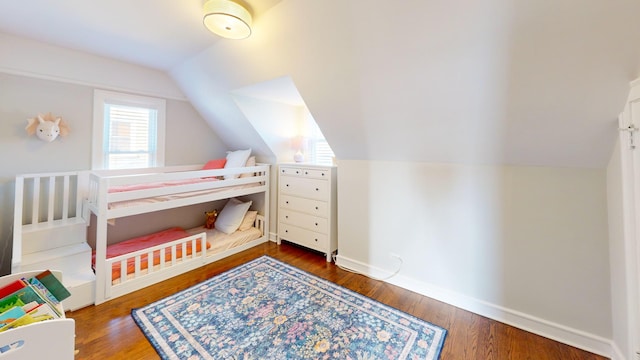 bedroom with dark wood-style floors, vaulted ceiling, and baseboards