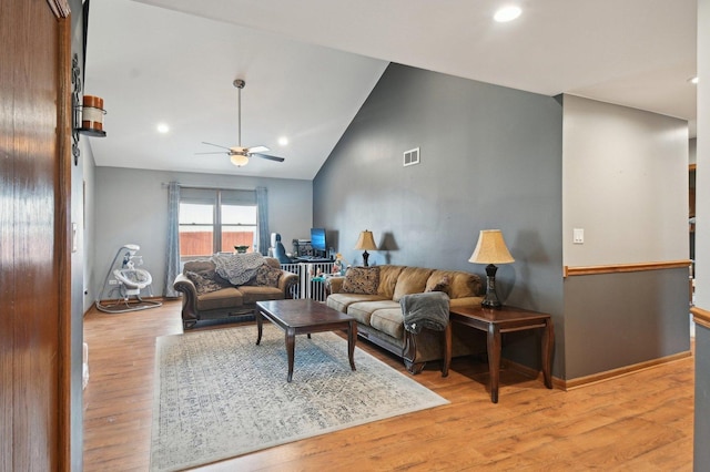 living room featuring lofted ceiling, visible vents, a ceiling fan, baseboards, and light wood-type flooring