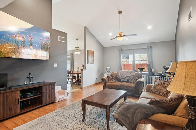 living room with lofted ceiling, a ceiling fan, visible vents, and wood finished floors