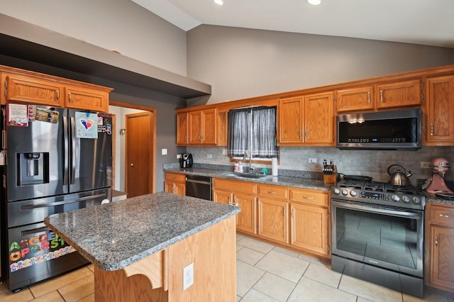 kitchen with stainless steel appliances, vaulted ceiling, brown cabinets, and a sink