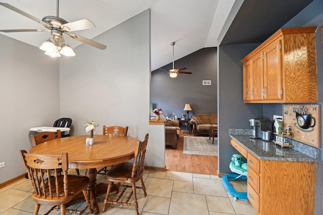 dining space featuring lofted ceiling, visible vents, a ceiling fan, light tile patterned flooring, and baseboards