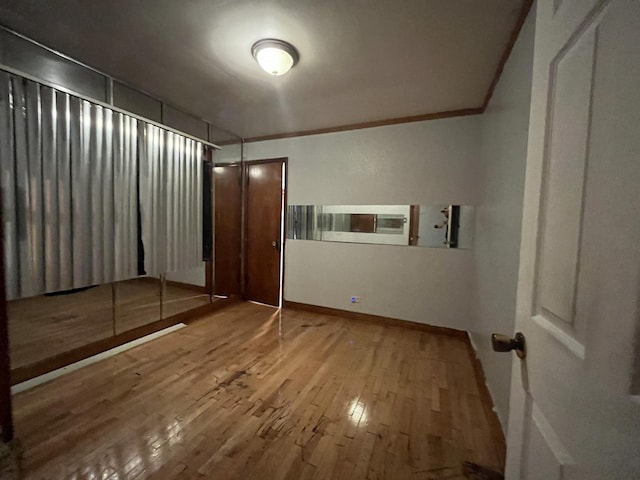 unfurnished bedroom featuring crown molding and wood finished floors