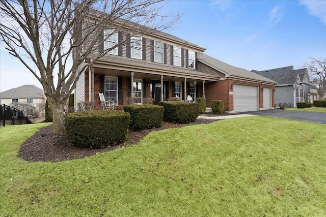 view of front of house with aphalt driveway, a front yard, brick siding, and an attached garage