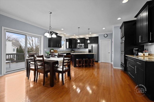 dining space featuring ornamental molding, recessed lighting, light wood-style flooring, and baseboards