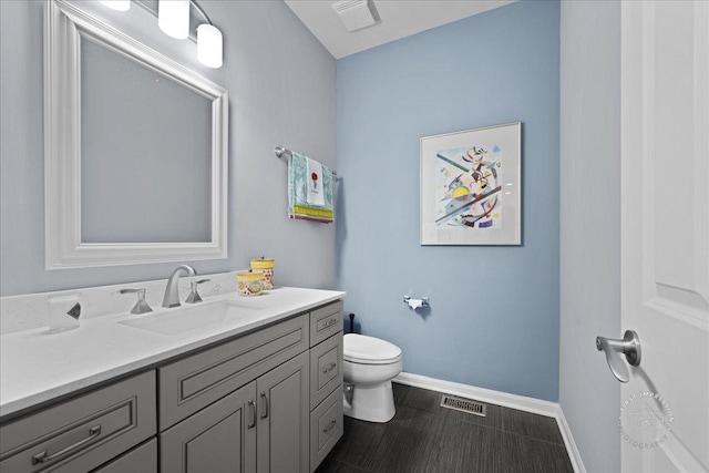 bathroom featuring toilet, vanity, visible vents, and baseboards