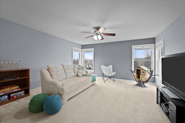 carpeted living area featuring a ceiling fan, baseboards, and a wealth of natural light