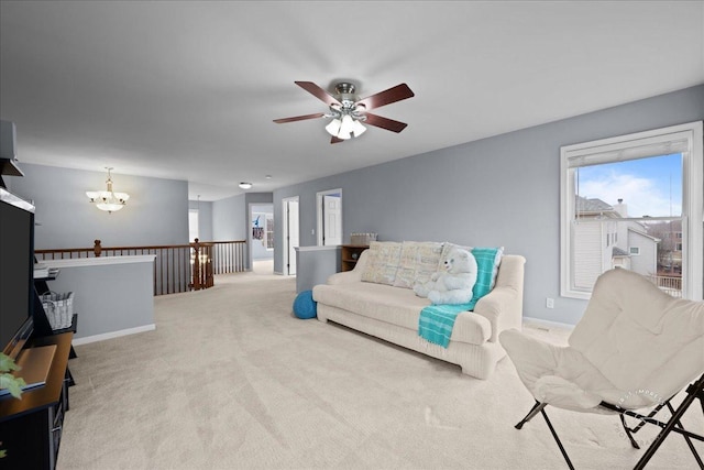 living room with carpet, baseboards, and ceiling fan with notable chandelier