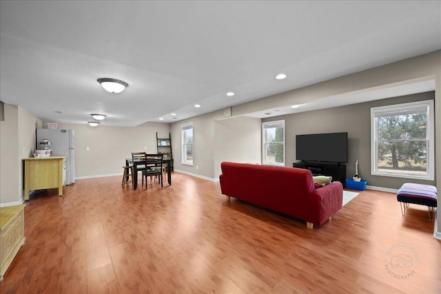 living area with baseboards, light wood finished floors, and recessed lighting