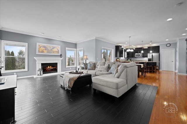 living room with baseboards, dark wood-style flooring, a lit fireplace, a chandelier, and recessed lighting