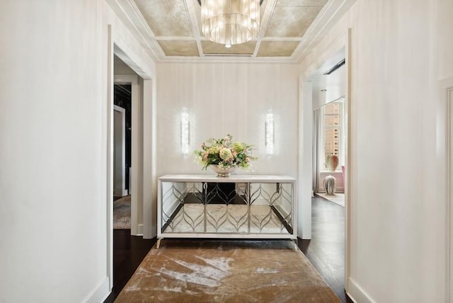 corridor with ornamental molding, a chandelier, coffered ceiling, and baseboards