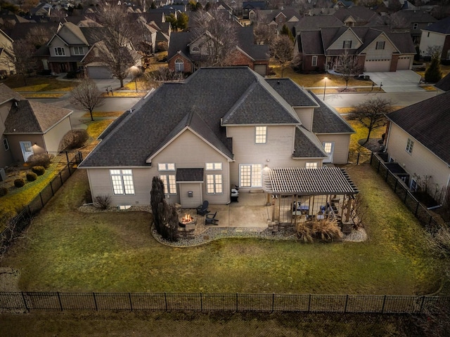 rear view of property with a fenced backyard, a shingled roof, a lawn, a residential view, and a patio area