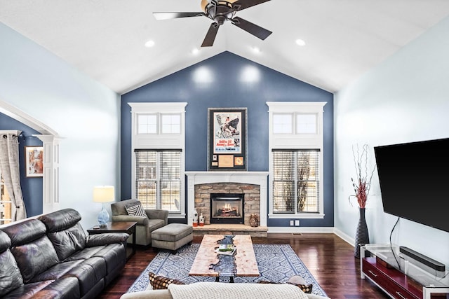 living room featuring high vaulted ceiling, a stone fireplace, wood finished floors, a ceiling fan, and baseboards