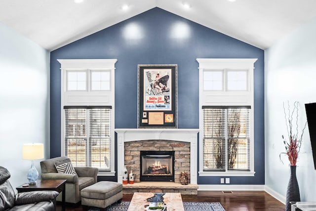 living area featuring baseboards, high vaulted ceiling, dark wood-type flooring, and a stone fireplace