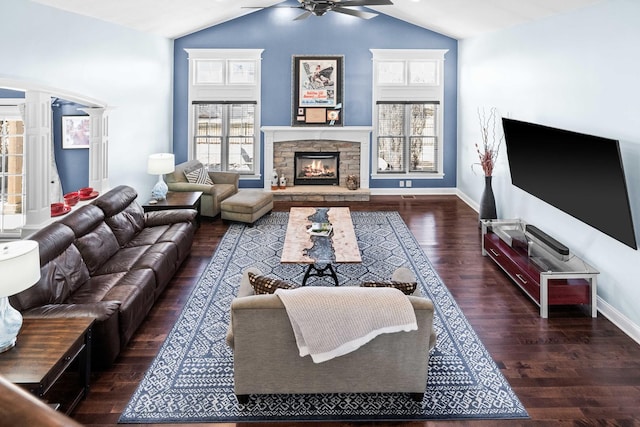 living room with baseboards, vaulted ceiling, wood finished floors, and a stone fireplace