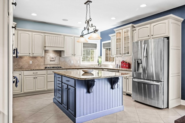 kitchen with light tile patterned floors, hanging light fixtures, appliances with stainless steel finishes, and a kitchen island