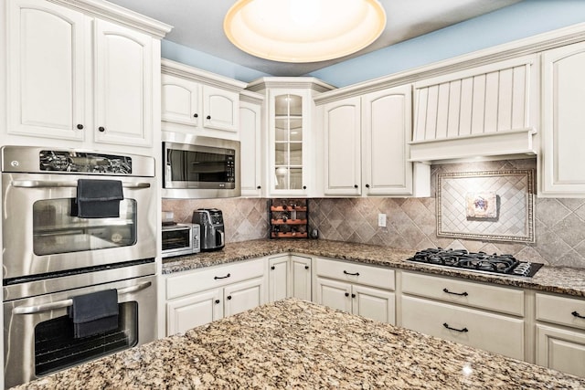 kitchen featuring stone countertops, appliances with stainless steel finishes, and backsplash