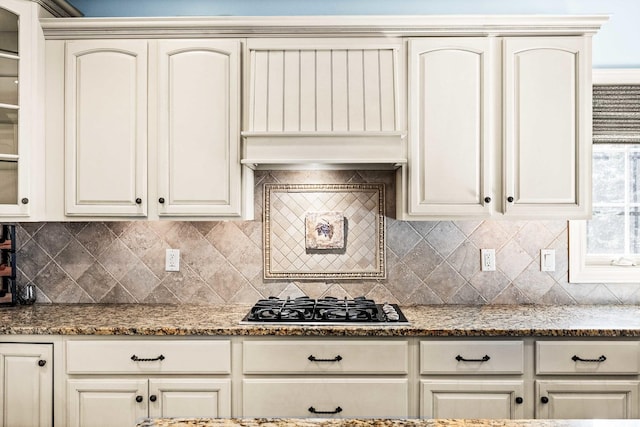 kitchen with glass insert cabinets, cream cabinetry, backsplash, and gas cooktop