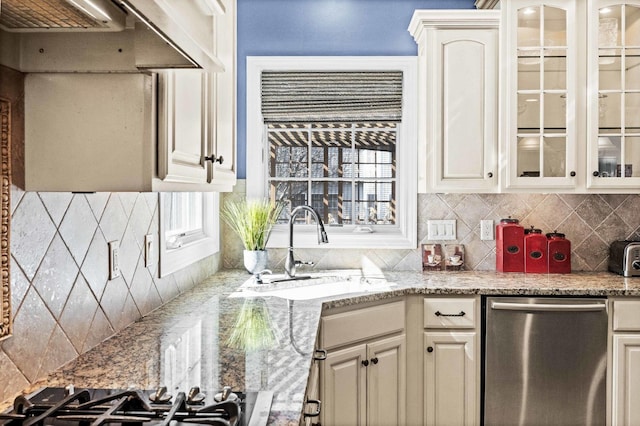 kitchen featuring decorative backsplash, glass insert cabinets, a sink, dishwasher, and under cabinet range hood