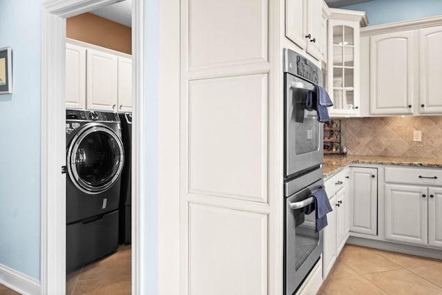 kitchen with washer / dryer, light tile patterned flooring, glass insert cabinets, and backsplash