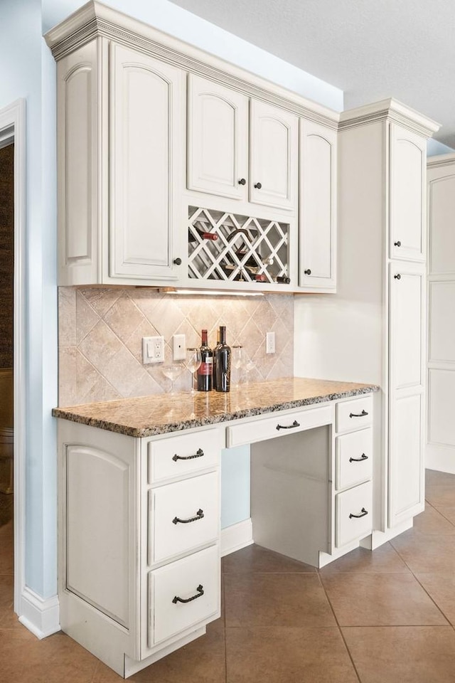 kitchen featuring light stone counters, backsplash, and tile patterned floors