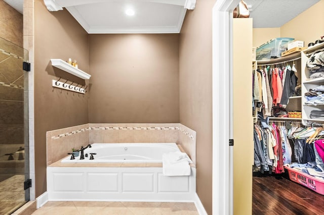 bathroom with a walk in closet, crown molding, a shower stall, baseboards, and a bath