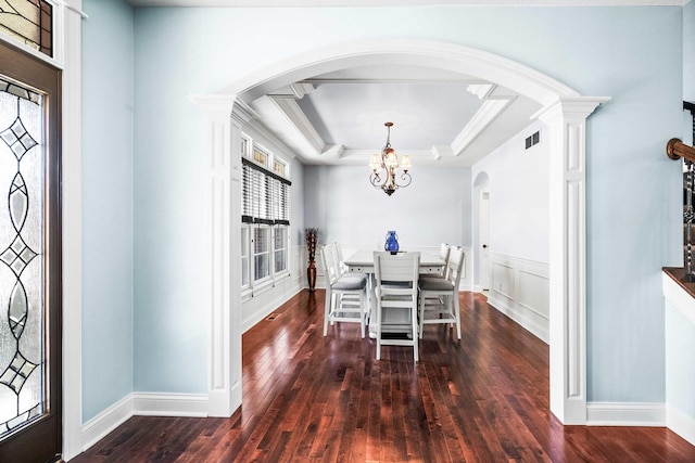 unfurnished dining area with arched walkways, a chandelier, dark wood-type flooring, visible vents, and a tray ceiling