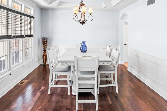 dining area with arched walkways, a raised ceiling, visible vents, and dark wood finished floors