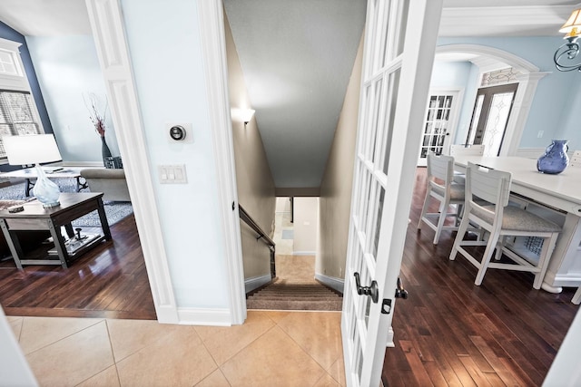 staircase featuring decorative columns, arched walkways, hardwood / wood-style floors, and french doors