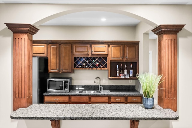 kitchen featuring stone countertops, stainless steel appliances, and a sink