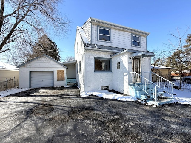 view of front facade with a garage, stucco siding, driveway, and an outbuilding