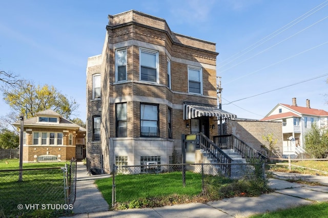 view of front of property featuring a fenced front yard, a front lawn, and brick siding