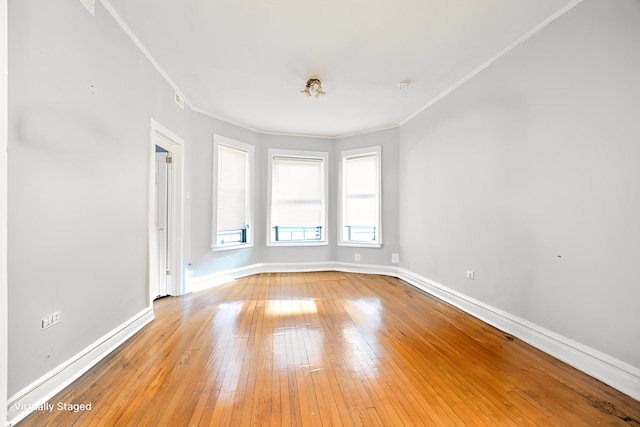 spare room featuring ornamental molding, light wood-type flooring, and baseboards