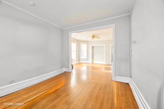 empty room featuring crown molding, light wood-style flooring, baseboards, and ceiling fan