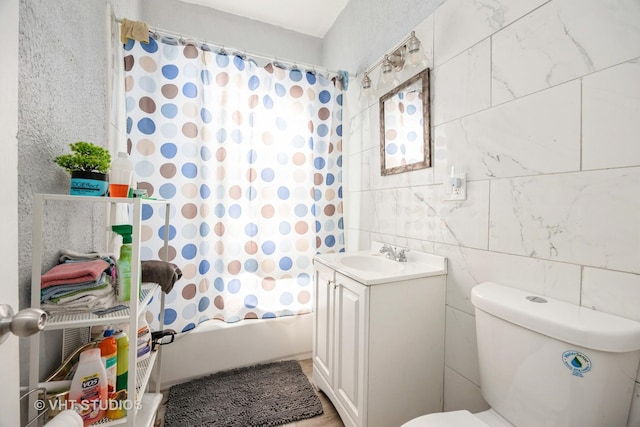 full bath with shower / bathtub combination with curtain, vanity, toilet, and tile walls