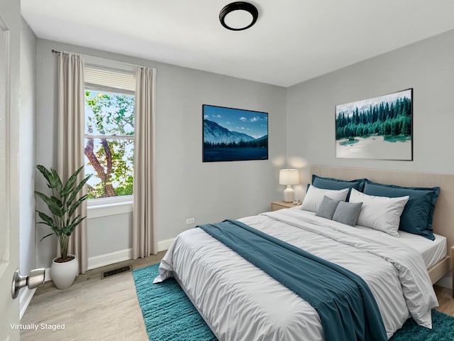 bedroom featuring light wood-style flooring, visible vents, and baseboards