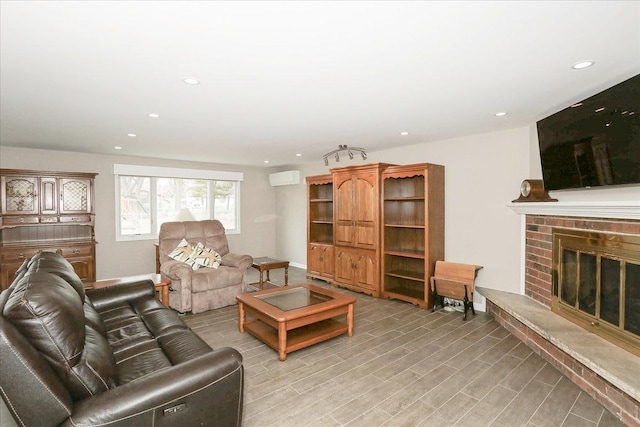 living room featuring a fireplace, recessed lighting, light wood-type flooring, a wall mounted air conditioner, and baseboards